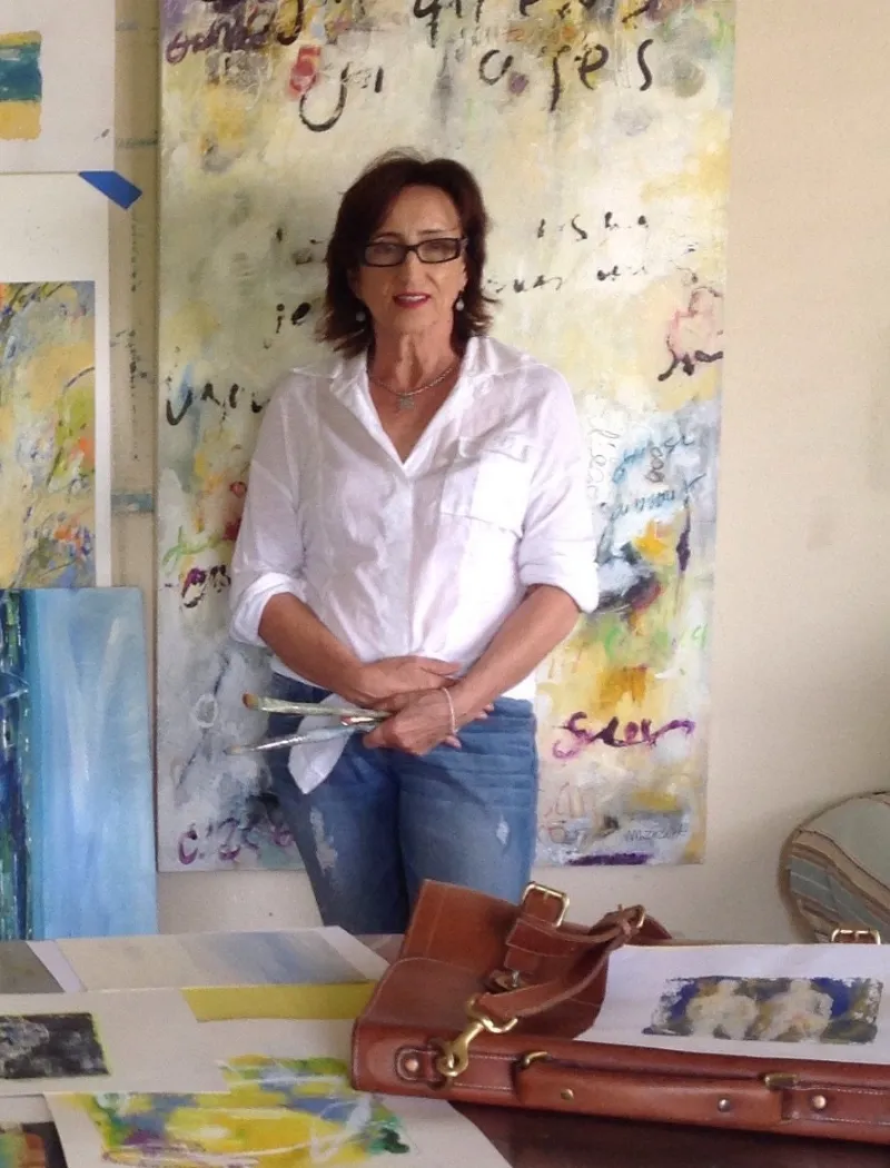 Michele Zuzalek standing in front of a large canvas of colour and handwritten text